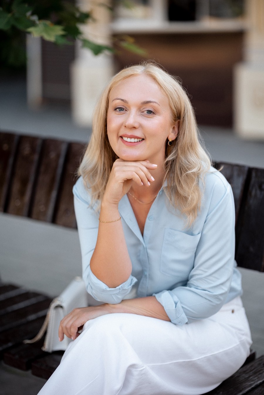 Svitlana in a pale blue shirt, resting her chin lightly on her hand and smiling