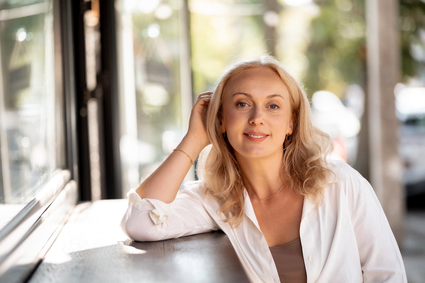 Svitlana Riabokin, hypnotherapist, leaning against a counter in a bright room and smiling warmly at the camera